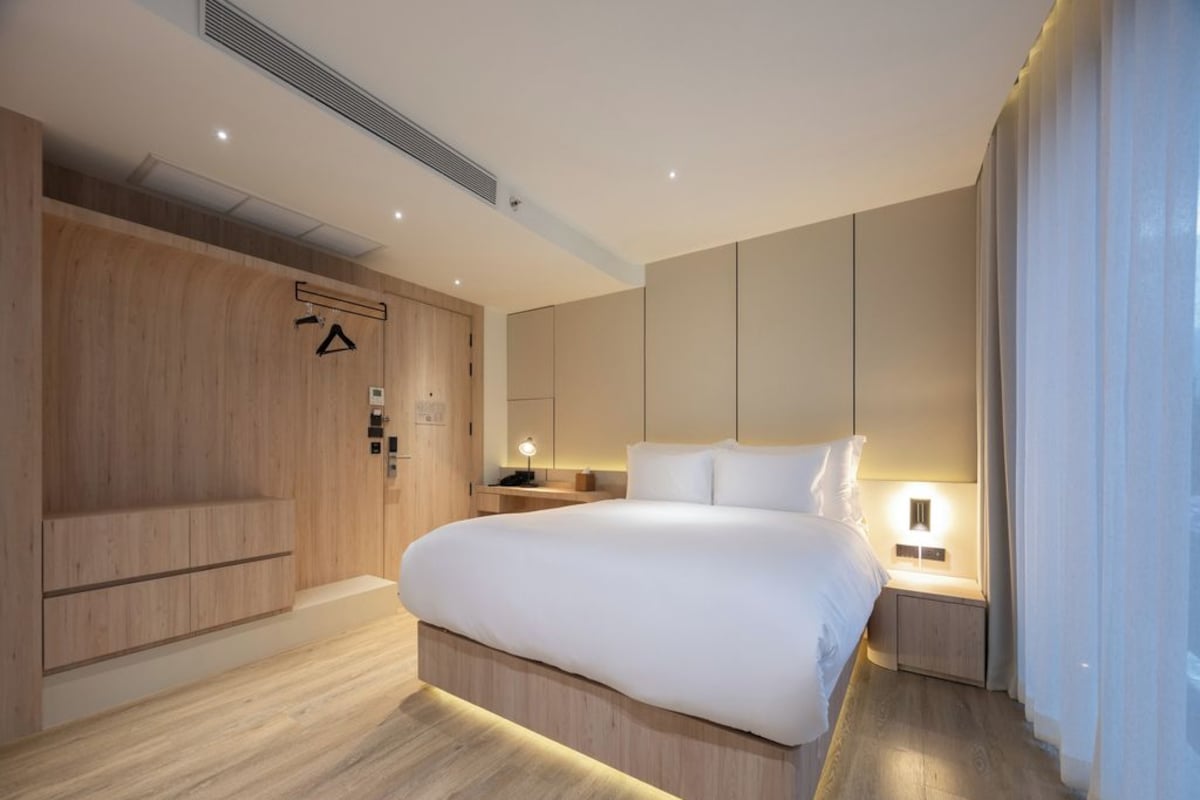 A modern bedroom with a large bed, wooden flooring, and built-in wardrobes.