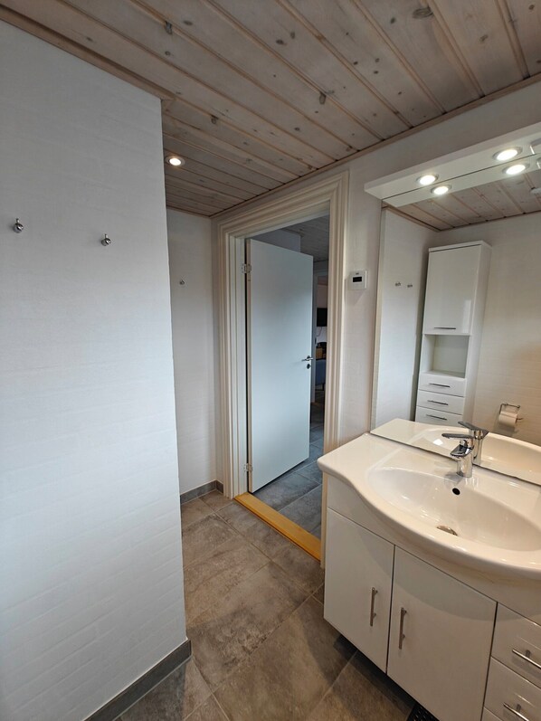 A modern bathroom with a white sink, mirror, and cabinets.