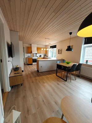 A modern kitchen with wooden cabinets, a central island, and a dining area with a table and chairs.