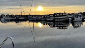 A marina with boats docked, calm water, and a sunset in the background.