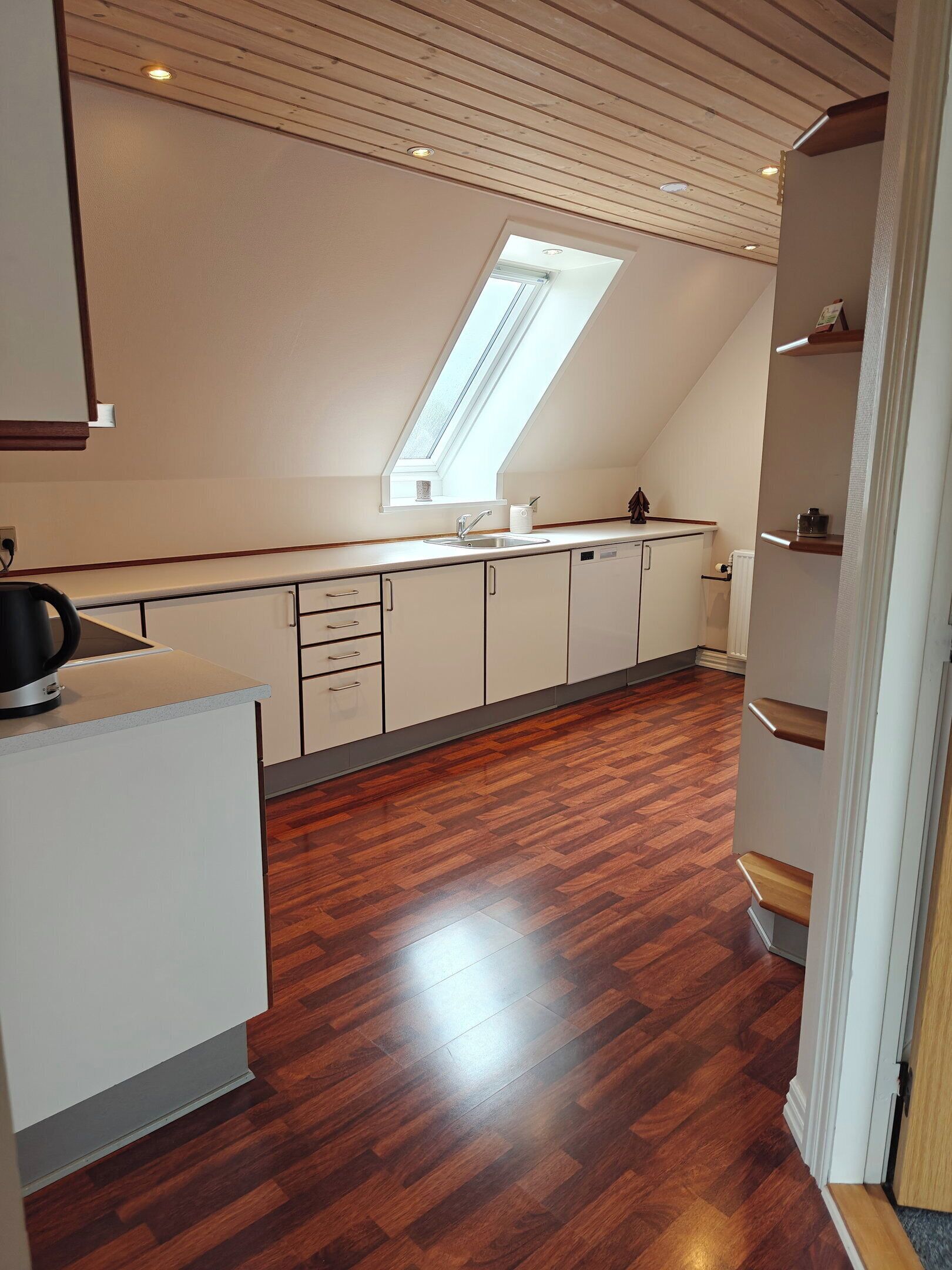 Una cocina moderna con tragaluz, suelo de madera y armarios blancos.