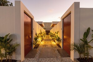 A modern building with a central pathway flanked by large wooden doors and potted plants.