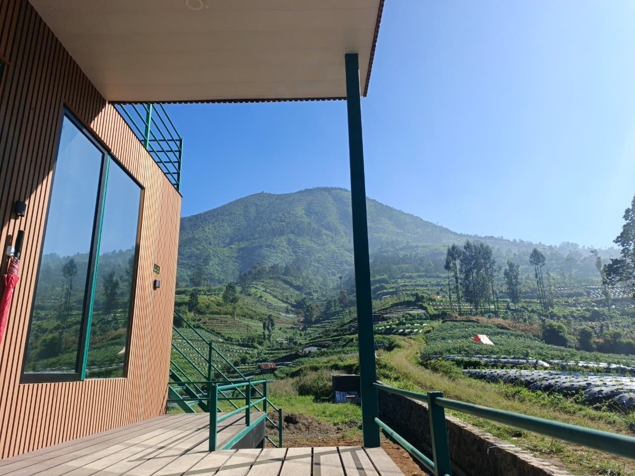 A wooden building with a balcony overlooking a hilly landscape.