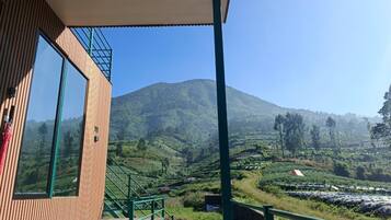 A wooden building with a balcony overlooking a hilly landscape.