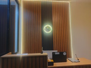 A reception desk with a logo, a computer, and a telephone. - 1440 MDPL Villa & Resort (Wonosobo)