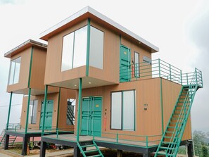 A modern multi-story building with a wooden facade, large windows, and green railings. - 1440 MDPL Villa & Resort (Wonosobo)