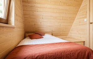 A small, wooden room with a bed, pillows, and a window. - Stunning home in Pepowo with WiFi (Pepowo)
