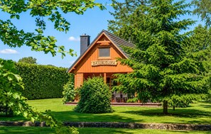 A wooden cabin with a sign reading 'DANIELOWKA' in a lush green setting.