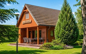 En stuga byggd av trä med en inglasad veranda och en möblerad uteplats.