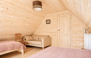 A cozy, sloped-roofed room with a bed, a sofa, and a chair. - Stunning home in Pepowo with WiFi (Pepowo)