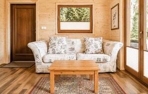 Ein Holzinterieur mit einer Couch, einem Holztisch und einem gemusterten Teppich.