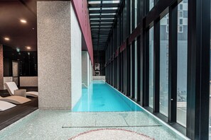 Ein Schwimmbecken mit Fliesenboden, einer Glaswand und einer roten Decke.
