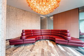 A modern interior with a curved red leather bench, a patterned floor, and a decorative ceiling light fixture. - Zen Sky Home - Super Centre w/ Carpark & Pool (Melbourne)