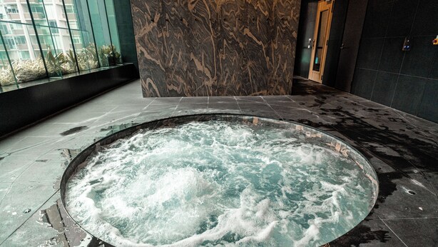 Ein Whirlpool mit Marmorwand und einem Glasfenster im Hintergrund.