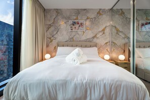 Une chambre d’hôtel avec un grand lit, un mur décoré d’un motif imitant le marbre et une vue sur la ville.