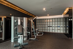 Une salle de sport moderne équipée de divers appareils d’exercice, dotée d’un mur de casiers et d’un sol ciré.