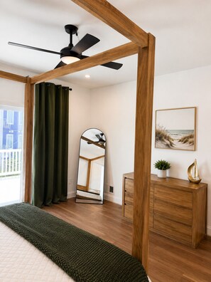 Ein Schlafzimmer mit einem Bett, einem Deckenventilator, einem Schminktisch, einem Spiegel und einem Bild an der Wand.