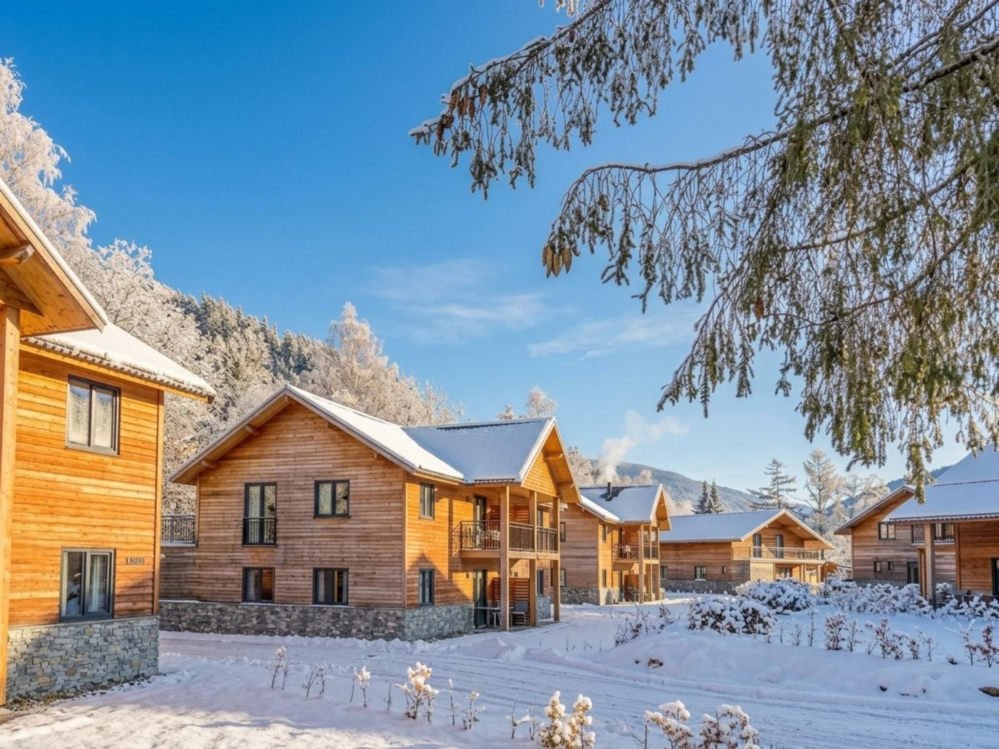 A row of wooden cabins with a stone foundation, set against a snowy landscape with clear skies.
