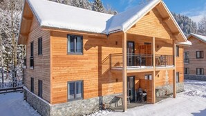 A wooden cabin with a balcony, stone foundation, and snow-covered surroundings. - Modern apartment with Alps and lake views (Afritz am See)