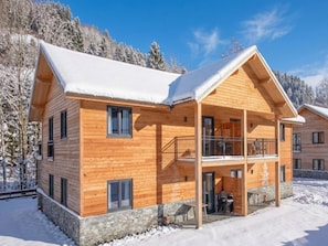 A wooden cabin with a balcony, stone foundation, and snow-covered surroundings. - Modern apartment with Alps and lake views (Afritz am See)