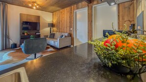 A modern living room with a sofa, a flat-screen TV, a coffee table, and a fruit basket. - Modern apartment with Alps and lake views (Afritz am See)