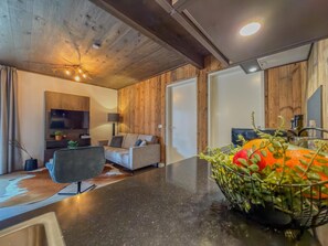 A modern living room with a sofa, a flat-screen TV, a coffee table, and a fruit basket. - Modern apartment with Alps and lake views (Afritz am See)