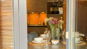 A dining area with a wooden table set for a meal, a vase with flowers, and a candle on the table. - Modern apartment with Alps and lake views (Afritz am See)