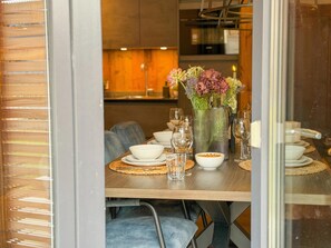 A dining area with a wooden table set for a meal, a vase with flowers, and a candle on the table. - Modern apartment with Alps and lake views (Afritz am See)