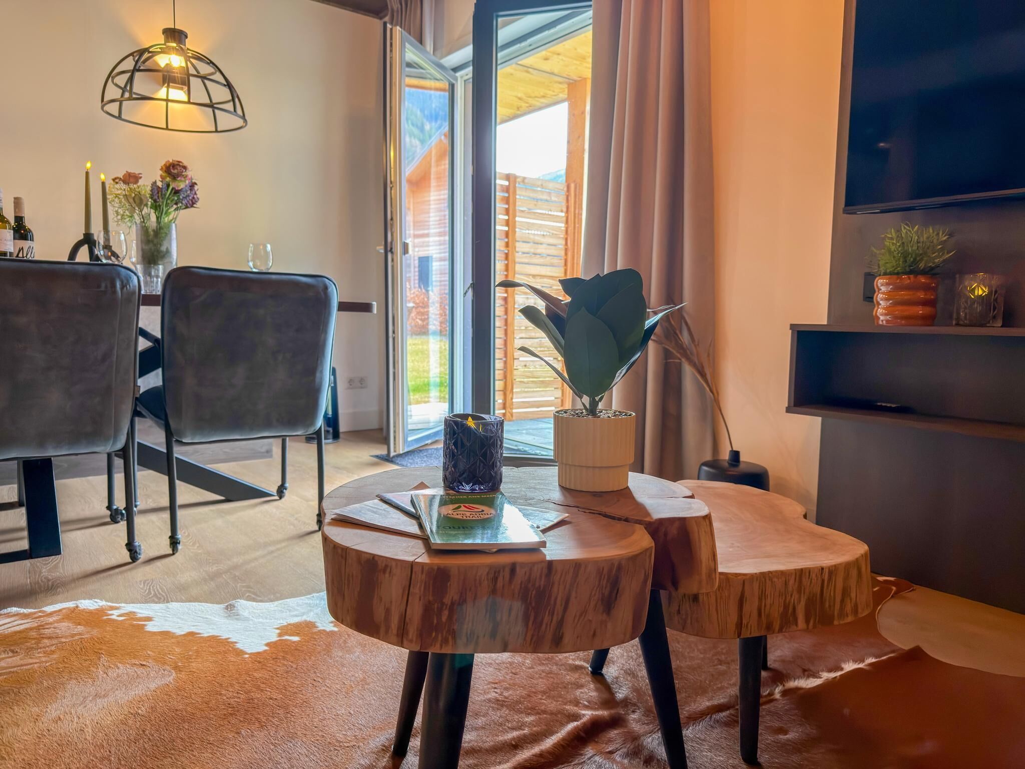 A modern living room with a round wooden coffee table, a leather sofa, and a dining area with chairs.