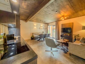 Une cuisine moderne avec un plan de travail noir et un coin repas comprenant une table et des chaises.