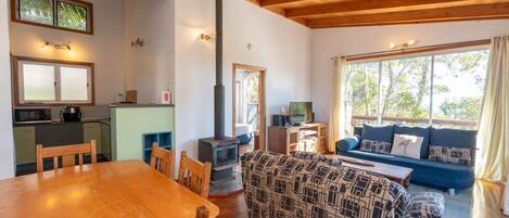 A cozy living area with a wooden dining table, a sofa, and a fireplace.