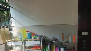 Un espace cuisine comprenant un étagère métallique où sont rangés divers ustensiles et récipients, un porte-couteaux fixé au mur et une porte avec une pancarte.