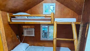 Une chambre avec un lit superposé, un plafond en bois, une petite fenêtre et un radiateur fixé au mur.