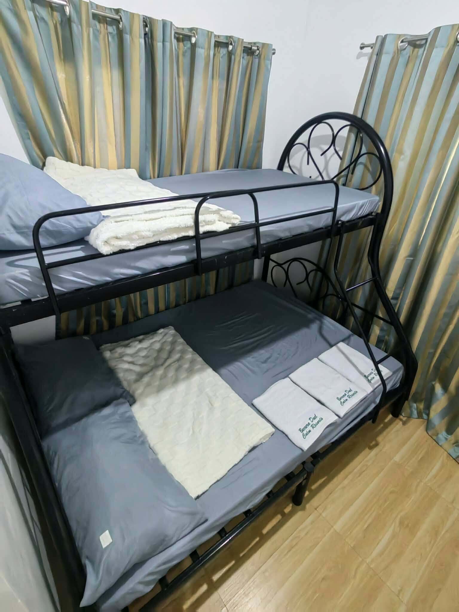 A bunk bed with a mattress and pillows, a metal headboard, and curtains.