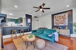 A modern living room with a teal sofa, wooden coffee table, and a ceiling fan. - Boho Serenity on the Southside- Workspace/Patio (Birmingham)
