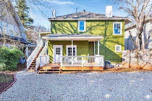 A two-story house with a front porch, a staircase, and a fenced yard. - Boho Serenity on the Southside- Workspace/Patio (Birmingham)