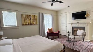 A hotel room with a bed, a chair, a fireplace, and a television. - Boho Serenity on the Southside- Workspace/Patio (Birmingham)