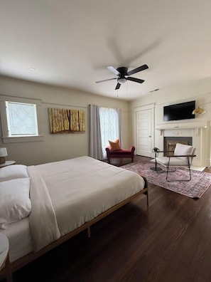 A hotel room with a bed, a chair, a fireplace, and a television. - Boho Serenity on the Southside- Workspace/Patio (Birmingham)