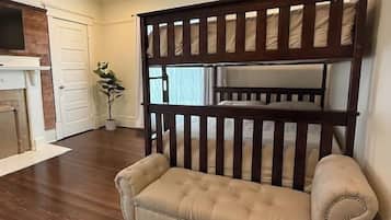 Een kamer met een houten stapelbed, een beige bank, een plafondventilator en een open haard.
