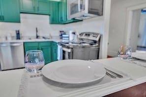 A dining table set with a plate, cutlery, and two glasses, with a kitchen in the background. - Boho Serenity on the Southside- Workspace/Patio (Birmingham)