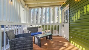 A covered outdoor area with wicker furniture, a glass table, and string lights. - Boho Serenity on the Southside- Workspace/Patio (Birmingham)