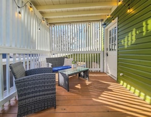 A covered outdoor area with wicker furniture, a glass table, and string lights. - Boho Serenity on the Southside- Workspace/Patio (Birmingham)