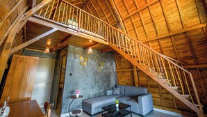 A wooden staircase leading to an upper level, a gray sofa, a small table, and a wall with framed artwork. - Topical 1BR A-Frame Villa Nakula Ubud (Ubud)