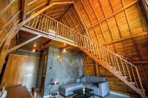 A wooden staircase leading to an upper level, a gray sofa, a small table, and a wall with framed artwork. - Topical 1BR A-Frame Villa Nakula Ubud (Ubud)