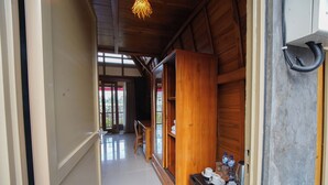 A hallway with wooden walls, a tiled floor, and a door leading to a room with a view. - Topical 1BR A-Frame Villa Nakula Ubud (Ubud)