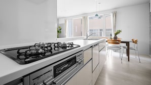 Una cocina moderna con estufa a gas, horno empotrado y comedor con mesa y sillas.