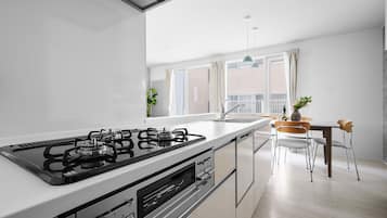 A modern kitchen with a gas stove, a built-in oven, and a dining area with a table and chairs.