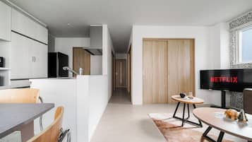 A modern kitchen with white cabinets, a black refrigerator, and a wooden door.
