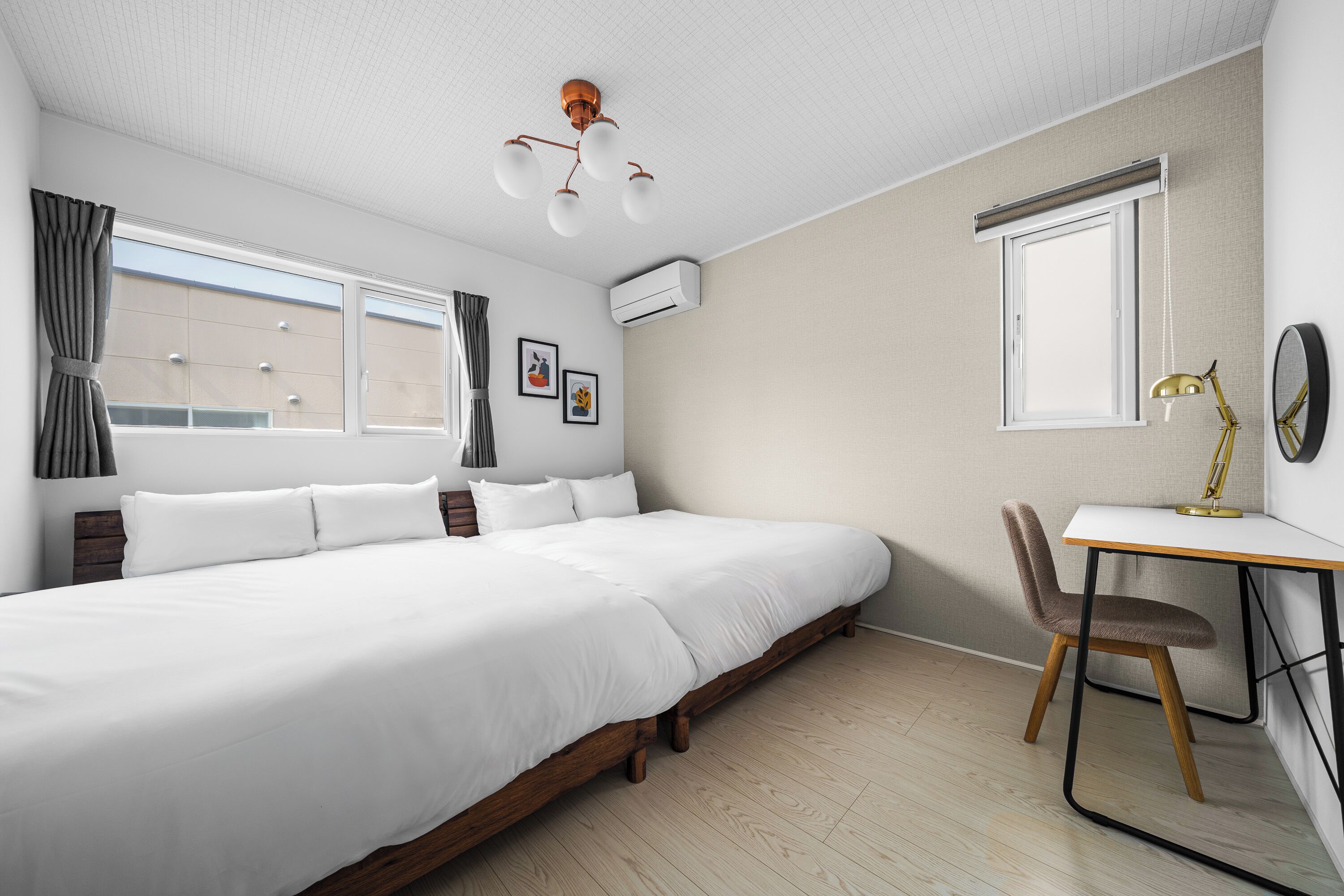 A modern bedroom with a large bed, a desk with a chair, and a window.