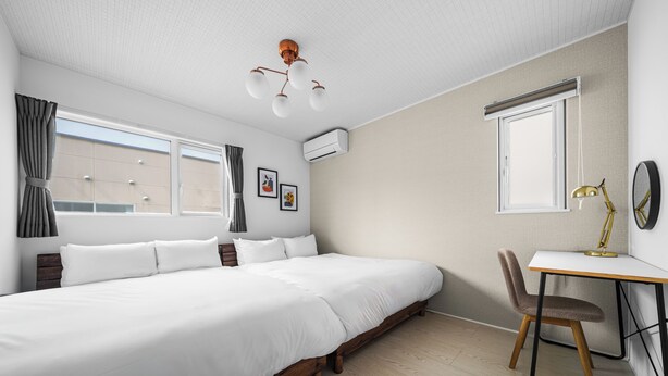 Un dormitorio moderno con una cama grande, un escritorio y una silla, y una ventana.